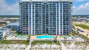 Un hôtel de grande hauteur doté de nombreux balcons, d’une piscine centrale et situé en bord de mer.