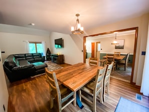 Un vaste espace de vie comprenant une table à manger en bois, un canapé en cuir noir et une cheminée.
