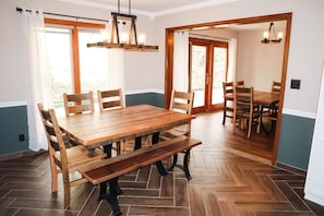 Un espace repas comprenant une table et des chaises en bois, un banc et un lustre.