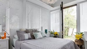 A bedroom with a bed, white nightstands, and a window with blinds. - Downtown Memphis 2 BR Eleanor Rigby suite Apt 101 (Memphis)