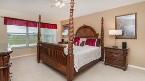 A four-poster bed with a wooden headboard, a nightstand with a lamp, and a dresser with drawers. - Exclusive 5 Star Villa with Private Pool on Windsor Palms Resort, Orlando Villa 4902 (Orlando)