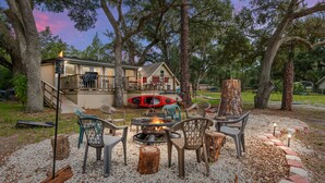 A patio area with outdoor seating, a fire pit, and a view of a house with a deck and a kayak. - FAMILY FOREST RETREAT, PARADISE AT POINT PLEASANT (Salt Springs)