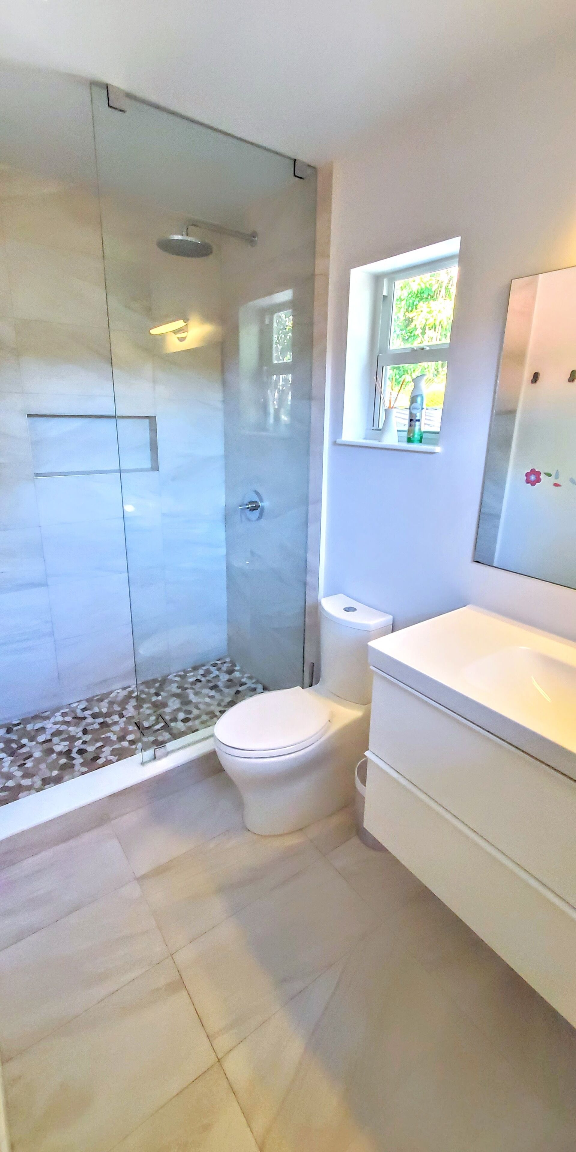 A bathroom with a glass-enclosed shower, a toilet, and a sink.