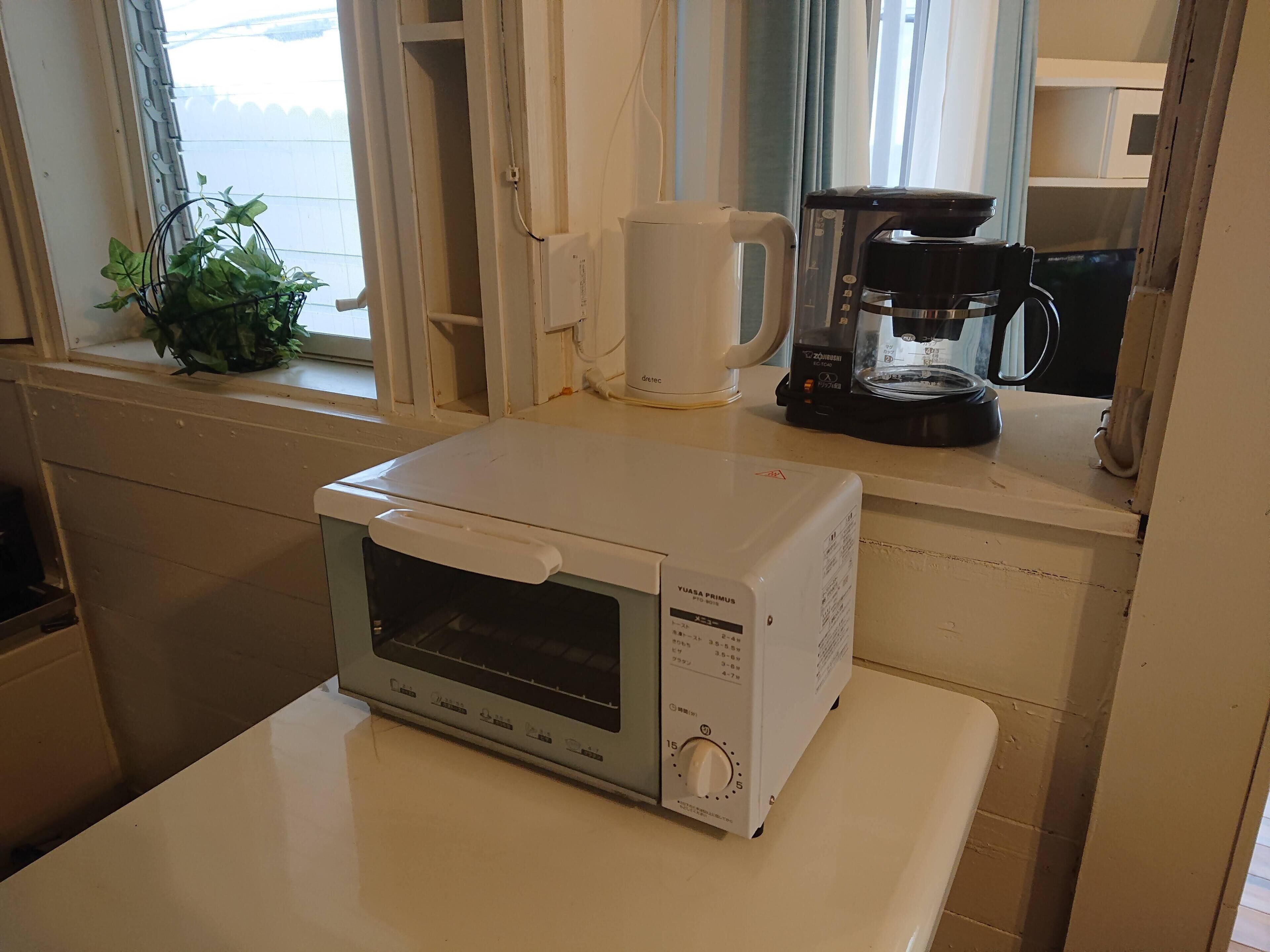 A compact kitchen with a microwave oven, a coffee maker, and a potted plant on the windowsill.
