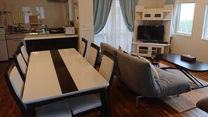 A compact living space with a dining table, chairs, a sofa, a TV, and a kitchenette. - Maribu Beach House (Onna)
