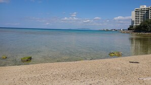 A beach with clear water, pebbles, and a building with balconies. - Maribu Beach House (Onna)