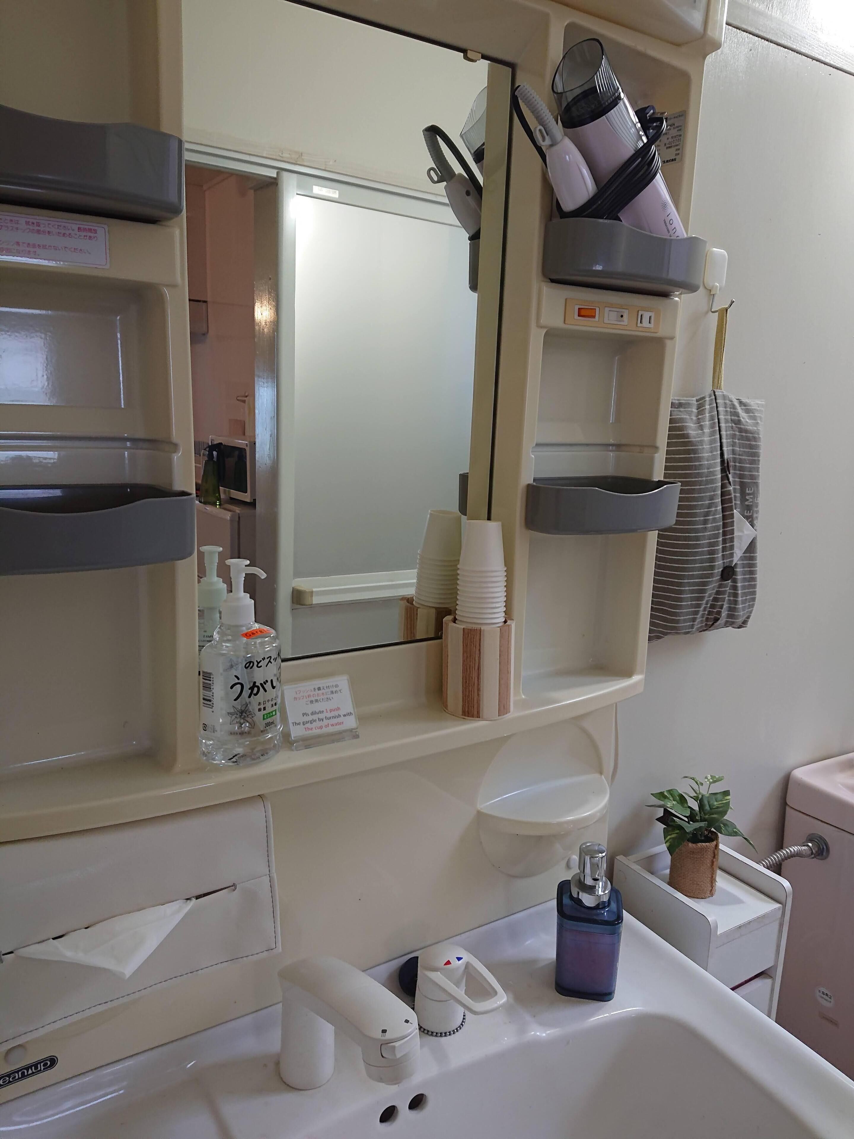 A bathroom with a sink, mirror, and various toiletries.