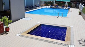 Et tagområde med pool, liggestole og et lille spabad.