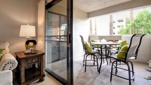 Quarto com porta de vidro que dá para área externa com cadeiras e mesa.