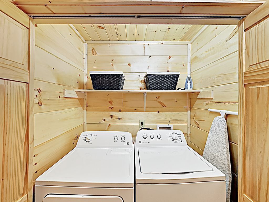 A compact laundry room with two washing machines and a shelf above them.