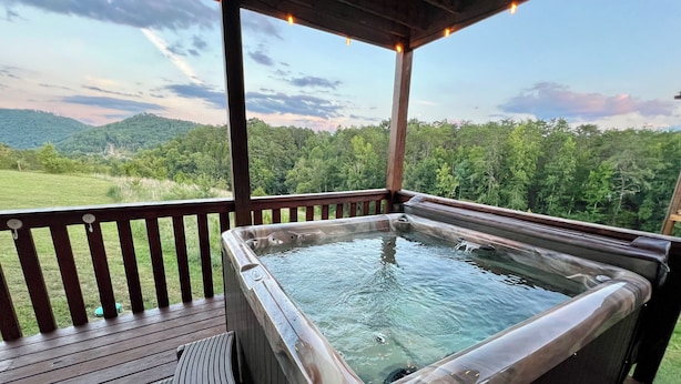 Un jacuzzi en una terraza de madera con vistas a un paisaje boscoso.