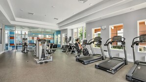 A gym with treadmills, weight machines, and a glass wall. - Awesome new dram vacation home 5 min. from Disney (Kissimmee)