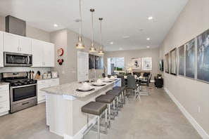 A modern kitchen with a central island, stainless steel appliances, and pendant lighting.