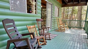 A log cabin with a porch featuring rocking chairs and a wooden table.