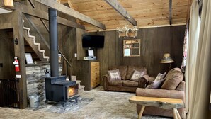 A cozy room with a stone fireplace, wooden furniture, and a television.