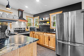 A modern kitchen with stainless steel appliances, wooden cabinets, and a black countertop.