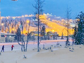 Ett snötäckt landskap med en skidbacke och byggnader i bakgrunden.