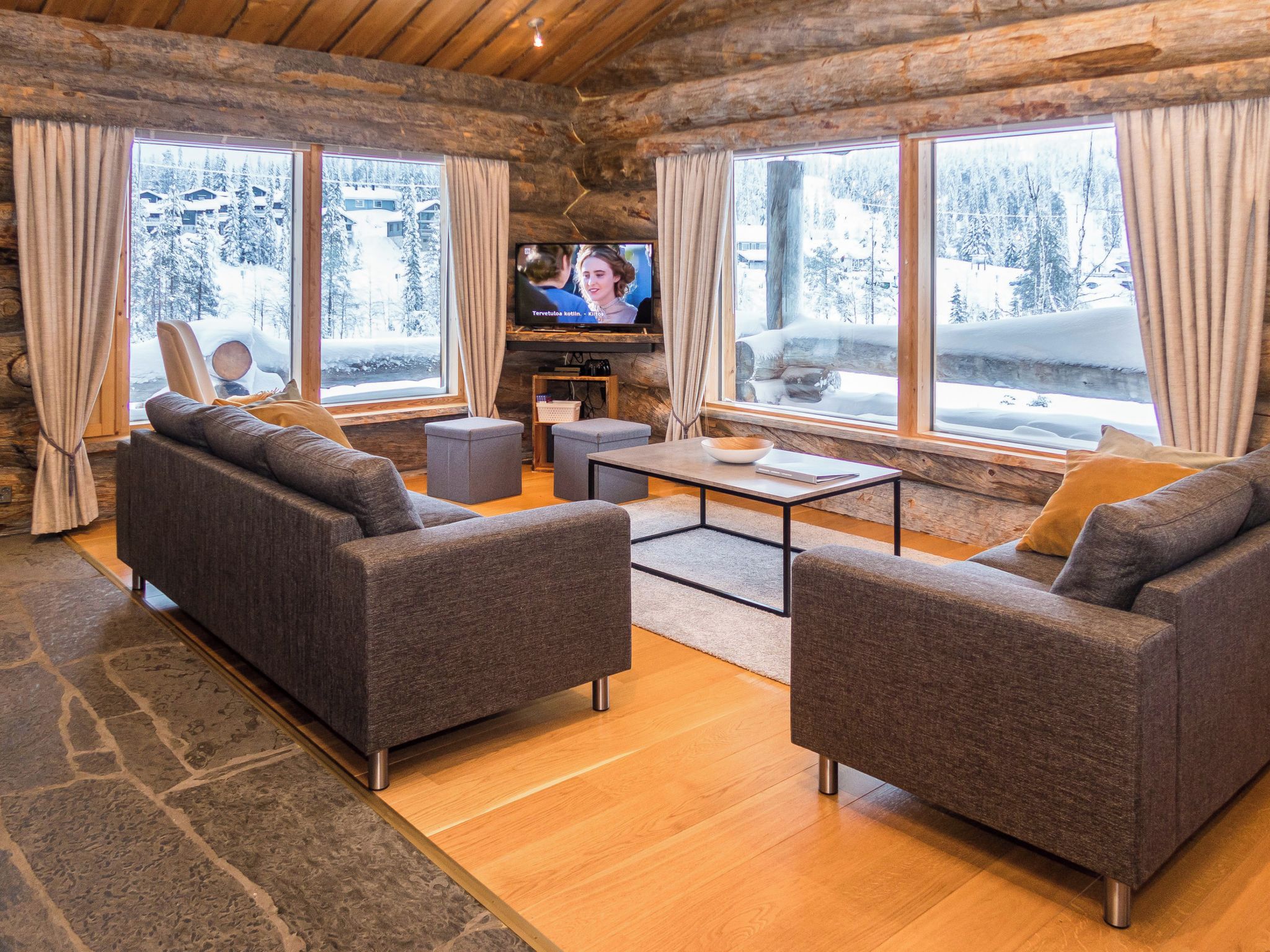 A cozy log cabin interior with a sofa set, a coffee table, and a television.