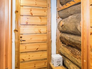 En dörr av trä med ett handtag och en vit låda med texten ”HELM SAUNA LAUDELINA” på, som står på en hylla.
