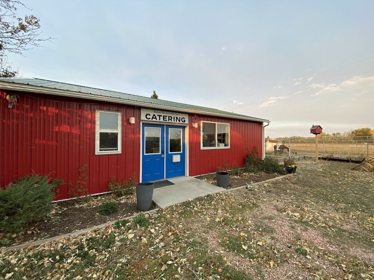 A red building with a blue door labeled "CATERING" and a small window.