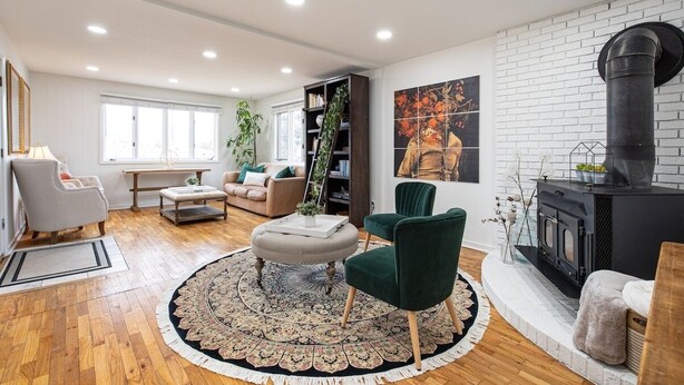 A modern living room with a fireplace, a round rug, and a bookshelf.