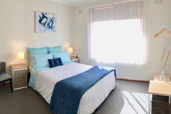 Bedroom with Queen bed, bedside drawers, Hanging racks and clothing shelf.