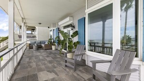 A covered outdoor area with a seating arrangement, potted plants, and large windows. - Kemah's Bayfront Getaway with Pool (Kemah)