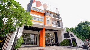 Un edificio moderno con estructura de varios pisos, grandes ventanales y un estacionamiento con motocicletas.