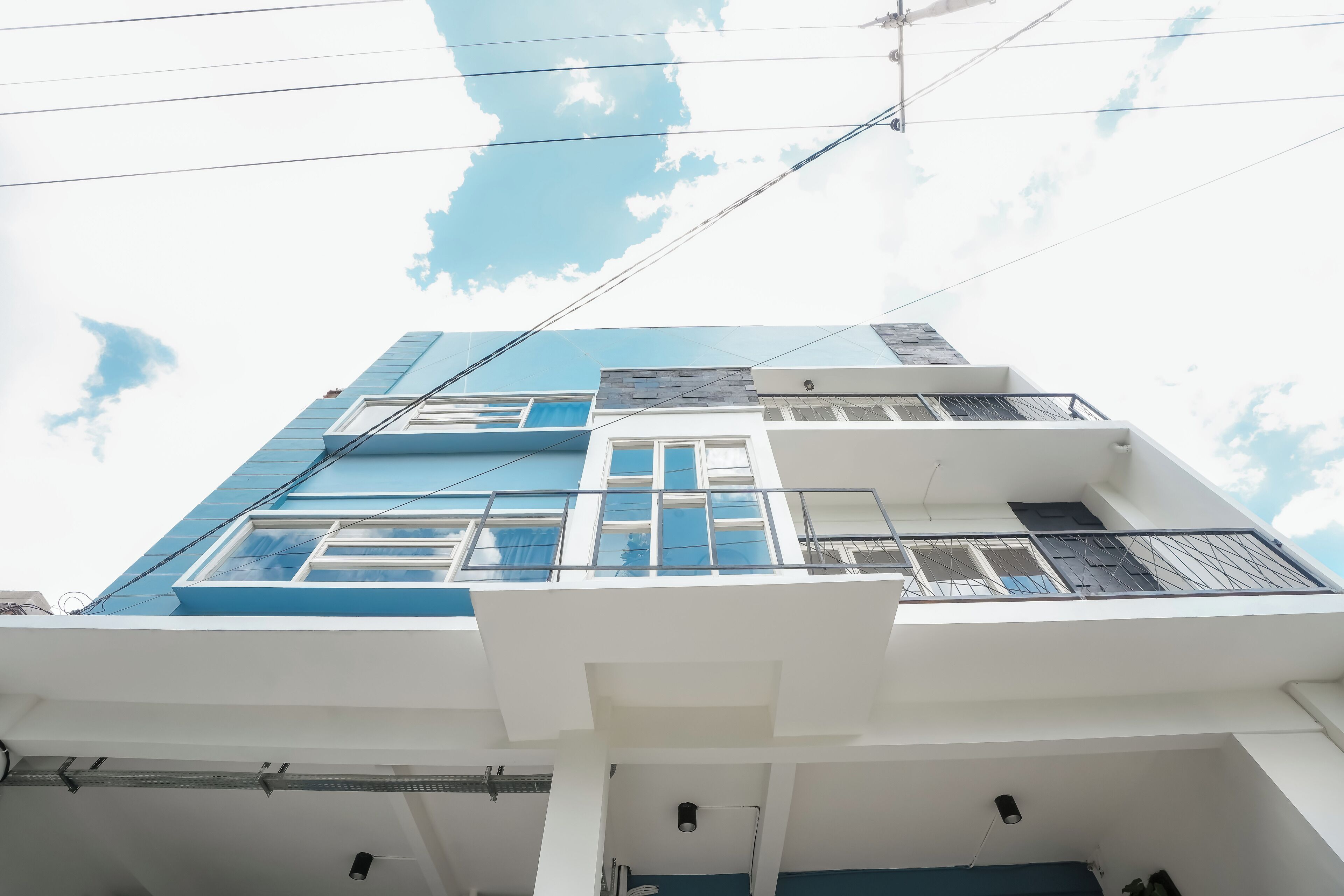 Un immeuble à plusieurs étages, doté d’une façade blanche et de touches de bleu, avec des balcons et de grandes fenêtres.
