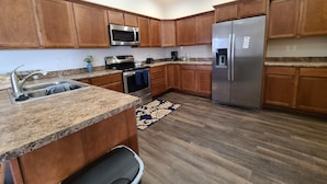 A modern kitchen with wooden cabinets, stainless steel appliances, granite countertops, and a kitchen island. - Beaverhead House Rental (Dillon)