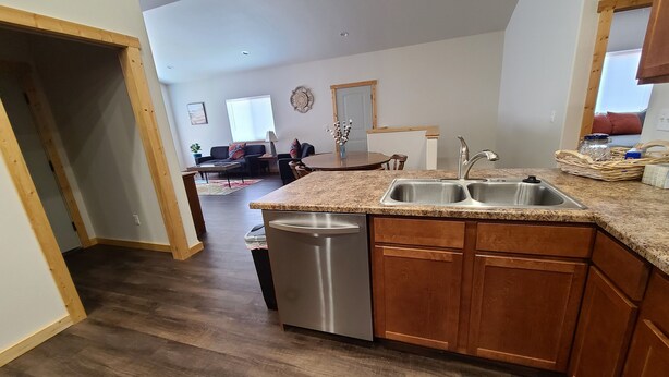 A modern kitchen with granite countertops, wooden cabinets, and a stainless steel dishwasher. - Beaverhead House Rental (Dillon)