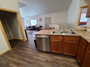 A modern kitchen with granite countertops, wooden cabinets, and a stainless steel dishwasher.