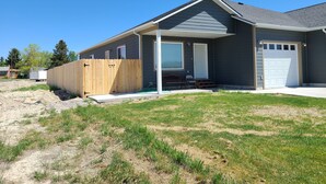 A residential house with a covered porch, a garage, and a fenced yard. - Beaverhead House Rental (Dillon)