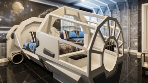 Ein Zimmer mit einem thematisch gestalteten Bett zum Thema Weltraum, einer Wandmalerei von Sternen und Planeten und einem geometrischen Deckenmuster.