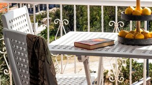 A balcony with a table, a chair, and a decorative lemon stand. - Poseidon Apartments (Skiathos)