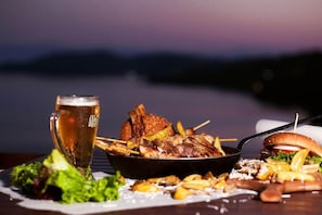 A meal with a burger, fries, and a beer on a table. - Poseidon Apartments (Skiathos)