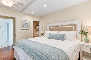 A bedroom with a bed, a nightstand, a lamp, a door, and a closet.