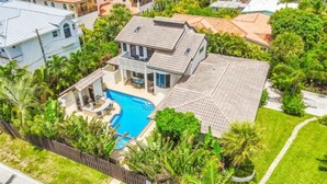 A large house with a swimming pool surrounded by lush greenery. - Just steps to the beach, sleeps 16, Golf cart, Dolphin Beach House huge pool! (Fort Lauderdale)
