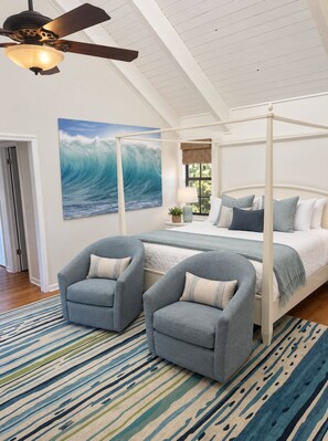 A bedroom with a four-poster bed, two armchairs, a large wave painting, and a ceiling fan. - Just steps to the beach, sleeps 16, Golf cart, Dolphin Beach House huge pool! (Fort Lauderdale)