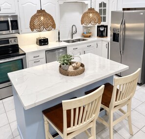 A modern kitchen with a central island, stainless steel appliances, and a coffee maker.