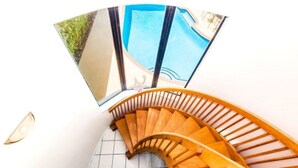 A spiral staircase with wooden handrails leading to a balcony with a pool view. - Just steps to the beach, sleeps 16, Golf cart, Dolphin Beach House huge pool! (Fort Lauderdale)