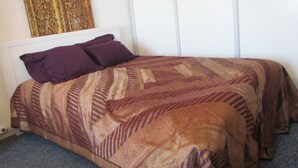 Un letto con copripiumino fantasia e due cuscini, un termosifone e un elemento decorativo a parete.
