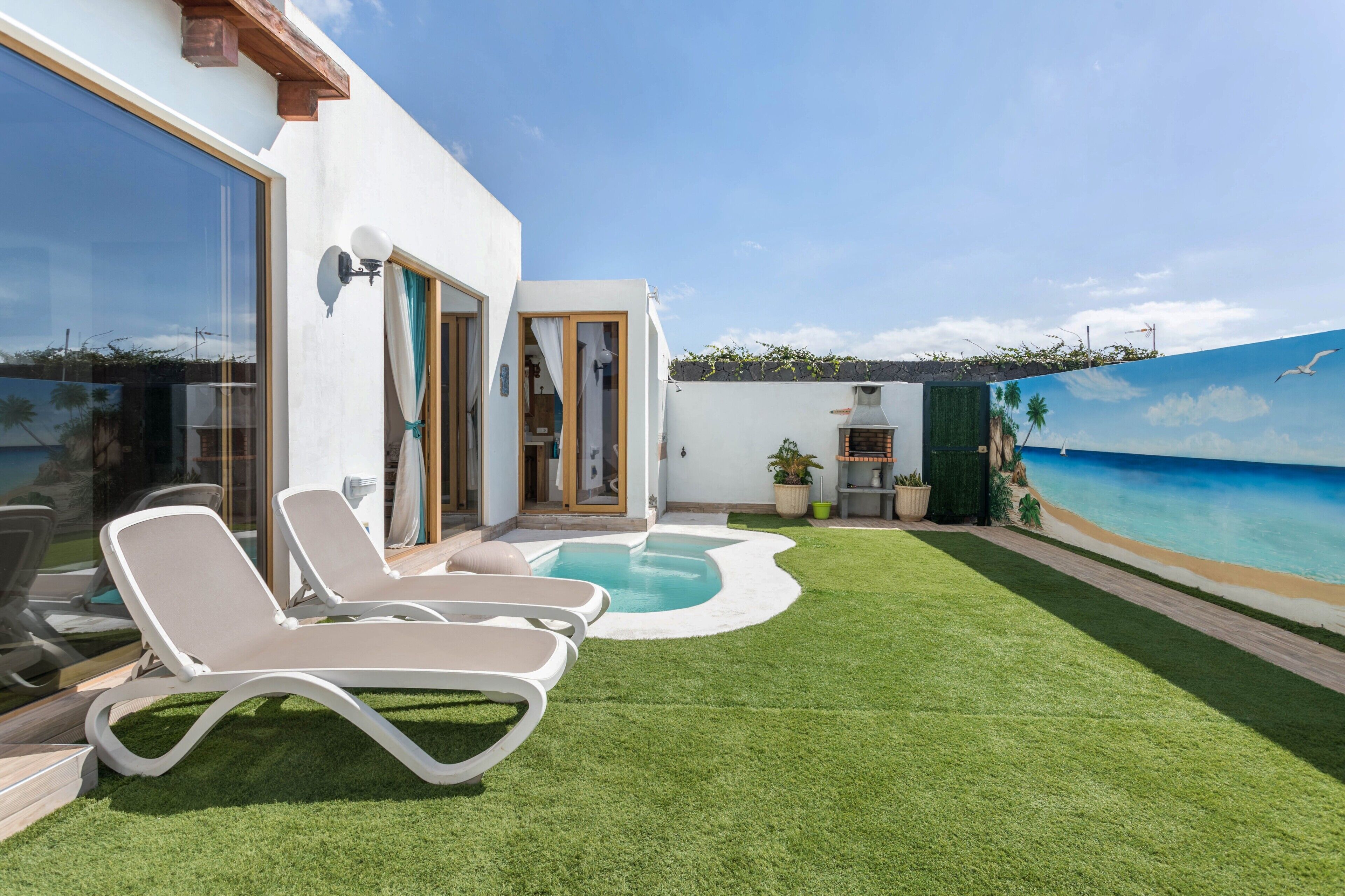 A modern outdoor pool area with lounge chairs, a small pool, and a view of the ocean.