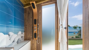 Une salle de bain avec douche, vue sur la plage et un mur carrelé.