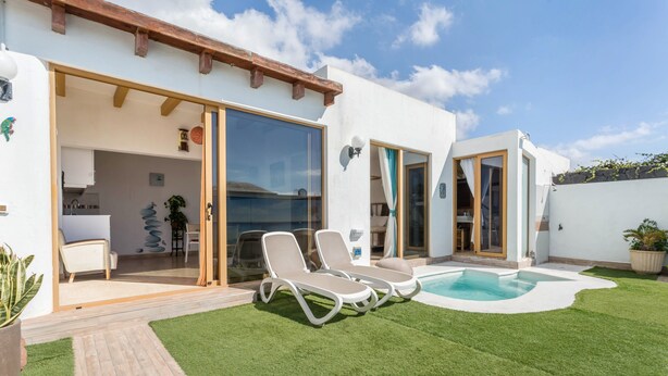 Une maison moderne dotée d’une piscine, de portes-fenêtres coulissantes et d’un espace patio.