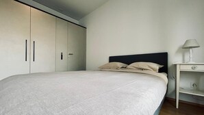 Une chambre à coucher avec un lit, une table de chevet et une armoire.