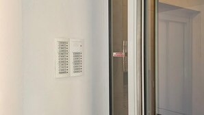 Un mur blanc avec une porte-fenêtre coulissante donnant sur un intérieur sombre.