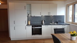 Una cocina moderna con armarios blancos, encimera negra, horno Siemens y ventana con vistas.