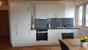 A modern kitchen with white cabinets, a black countertop, a Siemens oven, and a window with a view. - Vacation apartment Sunnseitn - Panoramahof Bergglück (Mellau)