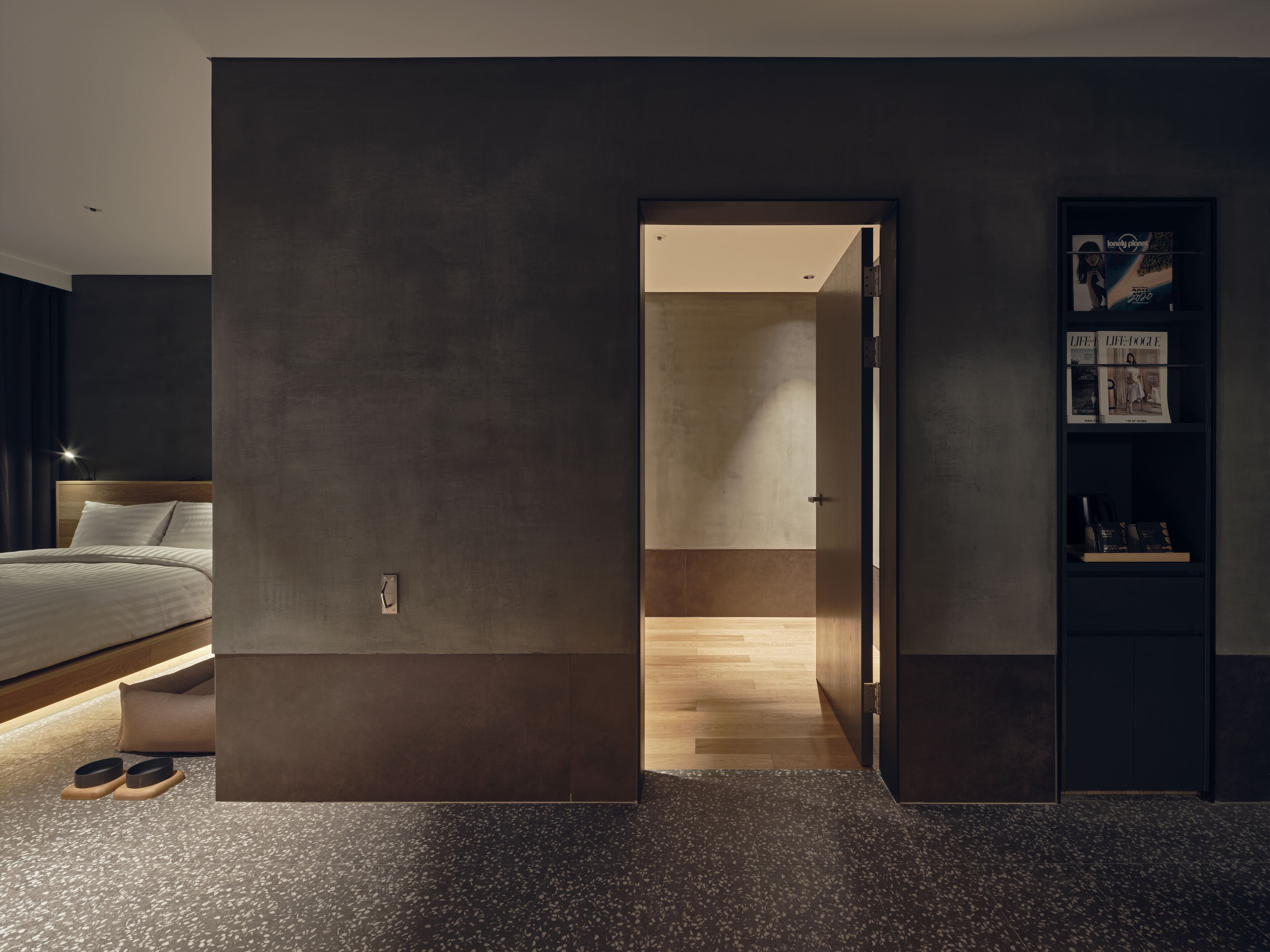 A modern bedroom with a bed, a wooden floor, and a dark wall.